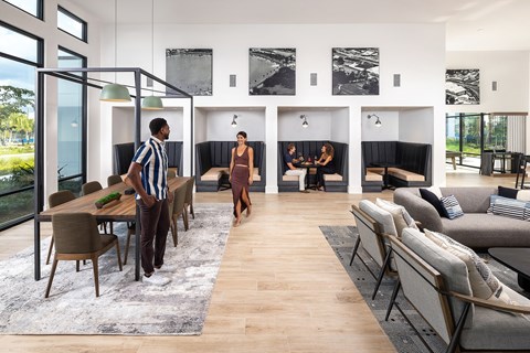 two people walking through a living room and dining room with a table and chairs